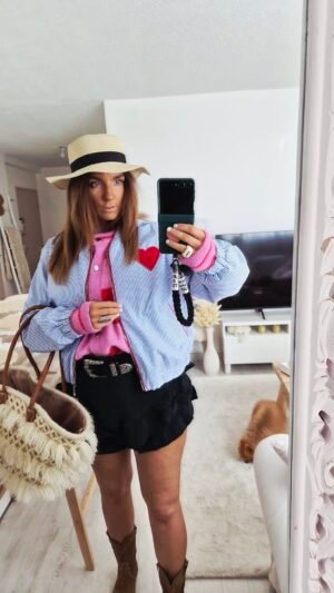 Une femme porte un blouson tendance casual bohème mi saison motif coeur rayée bleu et blanc pour la mi saison