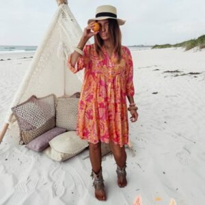 Robe bohème fluide imprimée rose et orange style californien portée sur la plage look été femme